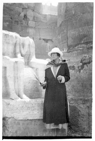 H.D., Egypt, 1923. Photo courtesy of Norman Holmes Pearson and New Directions Publishing Corp. Image shows H.D. with hat and scarf standing before the partial statue of a seated couple in ruins in Egypt.