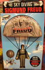Photo of a Sigmund Freud doll wearing a parachute with the label "Sky Diving Sigmund Freud" printed on the chute. 